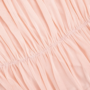 Macro detail of the light pink pleated mesh fabric with elegant ruching on the dress