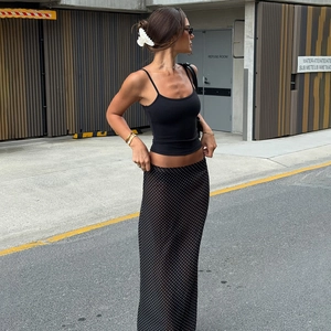 Detail of high-waisted black polka dot chiffon maxi skirt and slim fit crop tank top set