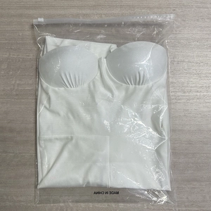 Détail d'un haut bustier blanc sans bretelles dans son emballage à glissière transparent