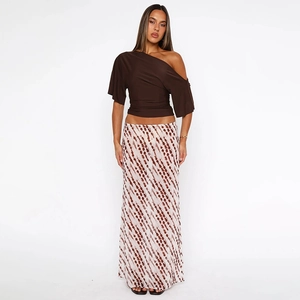 Detail view of woman in brown one-shoulder top and polka dot print maxi skirt
