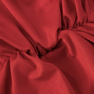 Gros plan détaillé du tissu côtelé rouge montrant la texture et le design froncé
