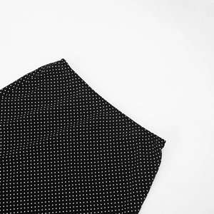 Close-up of lightweight chiffon fabric with classic white polka dots on a black base