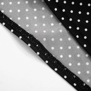 Detailed close-up of white polka dot print on black chiffon fabric with neat hem stitching