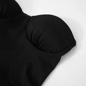 Gros plan des bonnets plissés sur une combinaison dos nu noire à texture mate