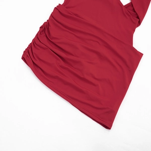 Détail des fronces latérales sur une robe moulante rouge foncé en tissu élastique