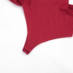 Gros plan sur un body rouge en tissu élastique lisse avec des fermetures à pression noires