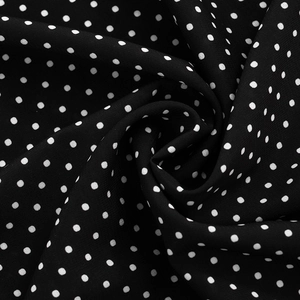 Close-up of black and white polka dot chiffon fabric showing soft drape and texture