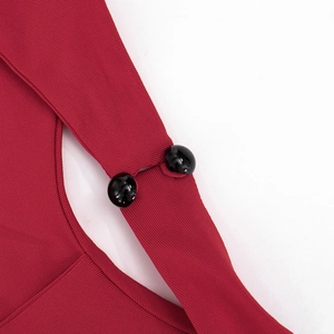 Détail du tissu en maille côtelée rouge foncé avec deux boutons sphériques noirs brillants