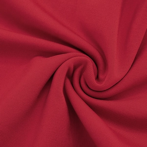 Gros plan sur le tissu en maille côtelée rouge foncé montrant élasticité et drapé
