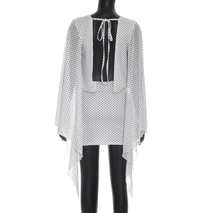 Detail of white polka dot dress featuring an open back design and flowing cape sleeves