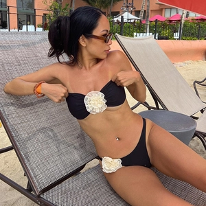 Close-up of black bikini set featuring oversized 3D white floral appliques on the beach
