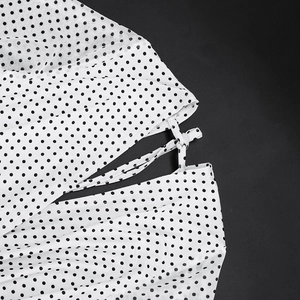 Detail of white fabric with black polka dots and mesh sleeve stitching on a summer dress