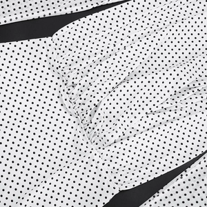 Detailed close-up of white mesh fabric with black polka dots and pleated texture details