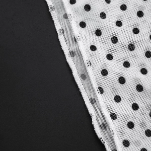 Detail of white mesh fabric featuring classic black polka dots and fine mesh texture