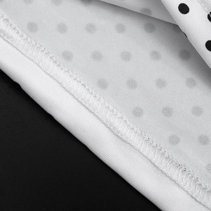 Detail shot of white polka dot fabric featuring precise overlock stitching on the hem