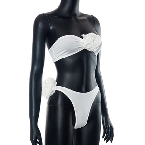 Detail of white tube top and bikini set featuring large 3D floral appliques on black mannequin