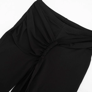 Detail of black high-waist pants featuring ruched design and pleated fabric texture