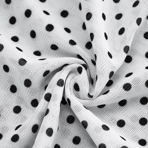Close-up of white mesh fabric with black polka dots and fine breathable texture