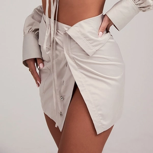 Detail of the high-waisted greige skirt with silver button and wrap-around waist design