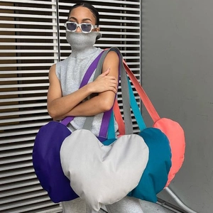 Modèle de style urbain portant un sac bandoulière en forme de cœur en nylon violet