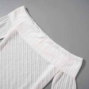 Detail of white ribbed knit fabric on off-shoulder top with focus on texture and stitching
