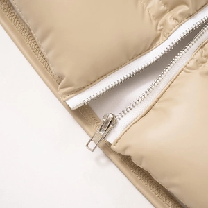 Détail d'une fermeture éclair argentée sur un gilet matelassé beige de qualité