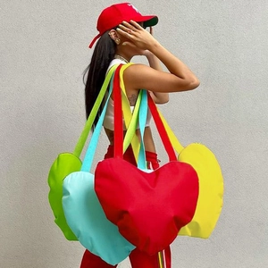 Modèle portant un grand sac cabas en forme de cœur en rouge et bleu vif très tendance