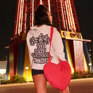 Détail d'un grand sac bandoulière rouge en forme de cœur porté avec un sweat streetwear