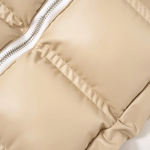 Détail d'un gilet matelassé en similicuir beige avec une fermeture éclair en métal argenté