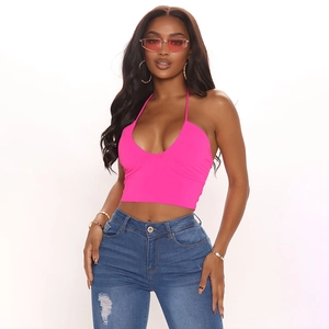 Bright pink halter top styled with ripped skinny jeans on a fashion model in studio