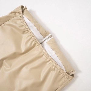 Détail du gilet en simili cuir kaki avec fermeture éclair blanche et taille élastiquée