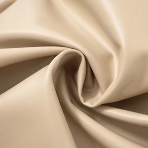 Gros plan sur cuir synthétique beige montrant une texture lisse et plis élégants