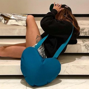 Sac fourre-tout bleu paon en forme de cœur présenté sur des marches en marbre chic