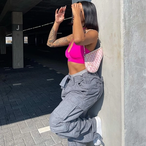Detail of grey multi-pocket cargo pants and pink halter top in a street style outfit