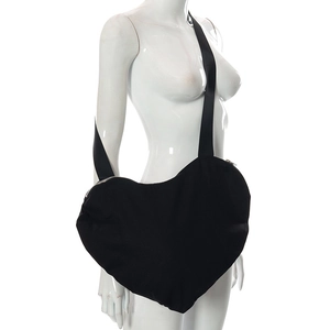 Détail d'un grand sac bandoulière noir en forme de cœur avec large sangle sur un mannequin
