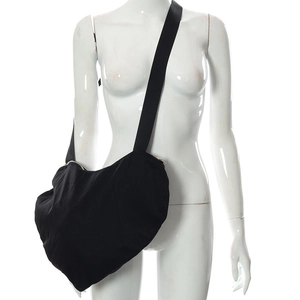 Détail du sac bandoulière noir en forme de cœur présenté sur un mannequin blanc