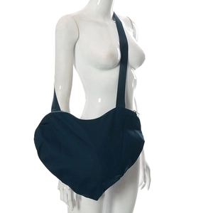 Détail du sac bandoulière en toile bleu marine en forme de cœur sur un mannequin