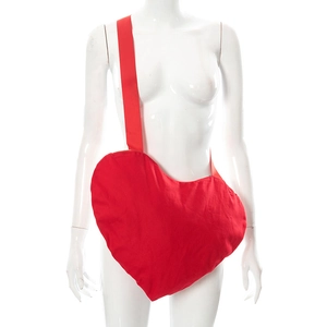 Détail du sac bandoulière rouge en forme de cœur avec large sangle sur un mannequin