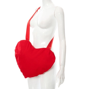 Détail du sac bandoulière rouge en forme de cœur sur mannequin montrant la texture