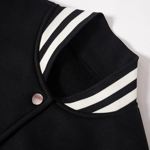 Detail der schwarzen Baseballjacke mit gestreiftem Rippkragen und silbernem Metalldruckknopf