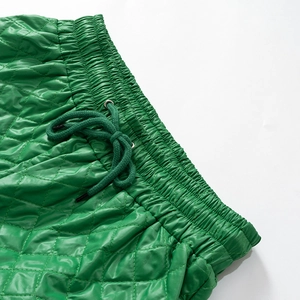 Detail of green quilted trousers showing elastic waistband and drawstring ties