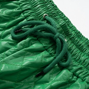 Close-up of bright green quilted fabric with drawstring waist and silver eyelets