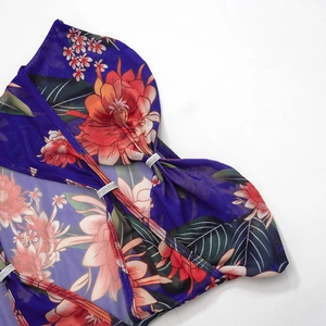 Detail van mesh stof met levendige bloemenprint en metalen gespen met strass