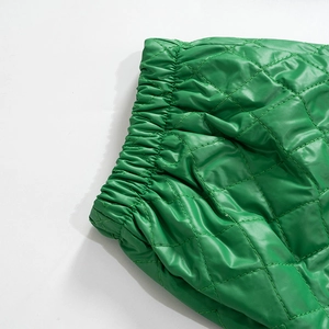 Detail of green quilted trousers showing elastic waistband and diamond stitched texture