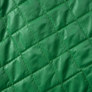 Macro shot of green quilted fabric with diamond pattern and precise stitching details