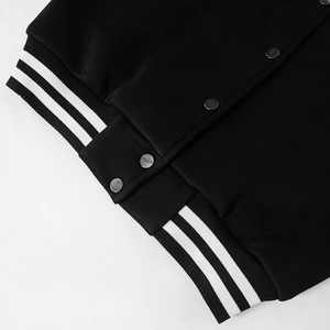 Detail von Metalldruckknöpfen und Rippbündchen an einer schwarz-weißen PU-Leder-Baseballjacke