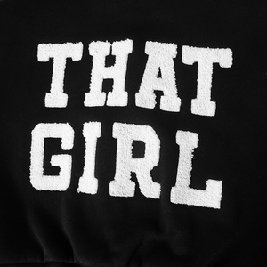 Detailansicht der weißen Chenille-Stickerei THAT GIRL auf schwarzer PU-Leder-Baseballjacke