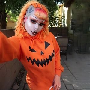 Dettaglio della stampa zucca di Halloween sull'abito con cappuccio arancione a maniche lunghe