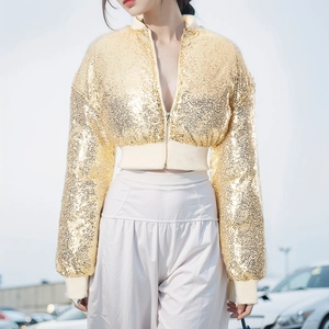 Detailed view of shimmering gold sequin texture and ribbed cuffs on a cropped bomber jacket