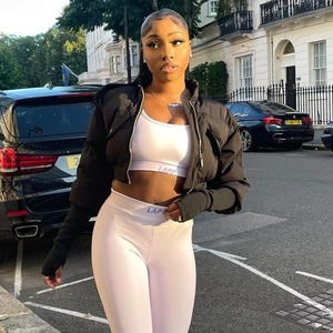 Women's black cropped puffer jacket with white sports bra and high-waist leggings set